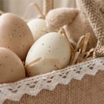 Detailaufnahme eines personalisierten Osterkörbchens aus Jute mit Spitzenbordüre und Satinschleife