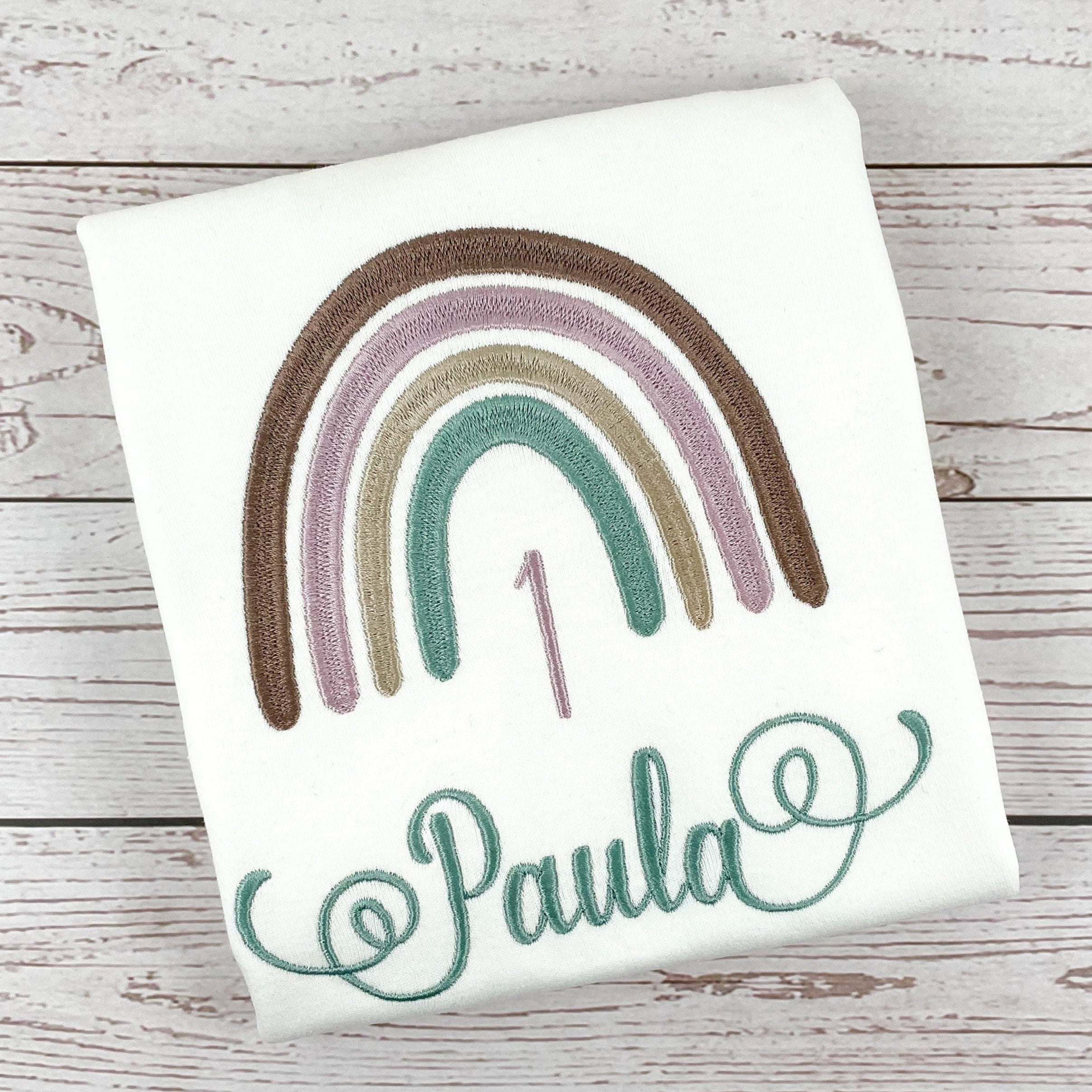Geburtstagsshirt mit Boho Regenbogen, personalisiert mit Name und Geburtszahl. Farben des Regenbogen - braun, lila, beige, mint. Schrift mit schnörkeln am Anfang und Ende.