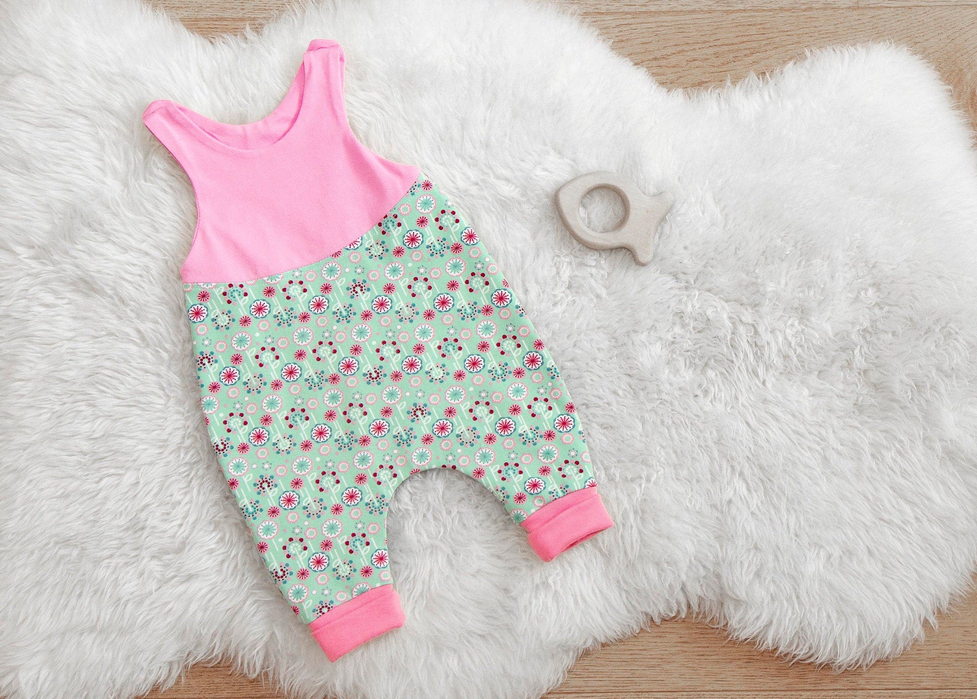 Babystrampler rosa / mint mit Blumen. Zweigeteilt, oben rosa unten mint mit Blumen in rosa. Passende Bündchen in rosa.