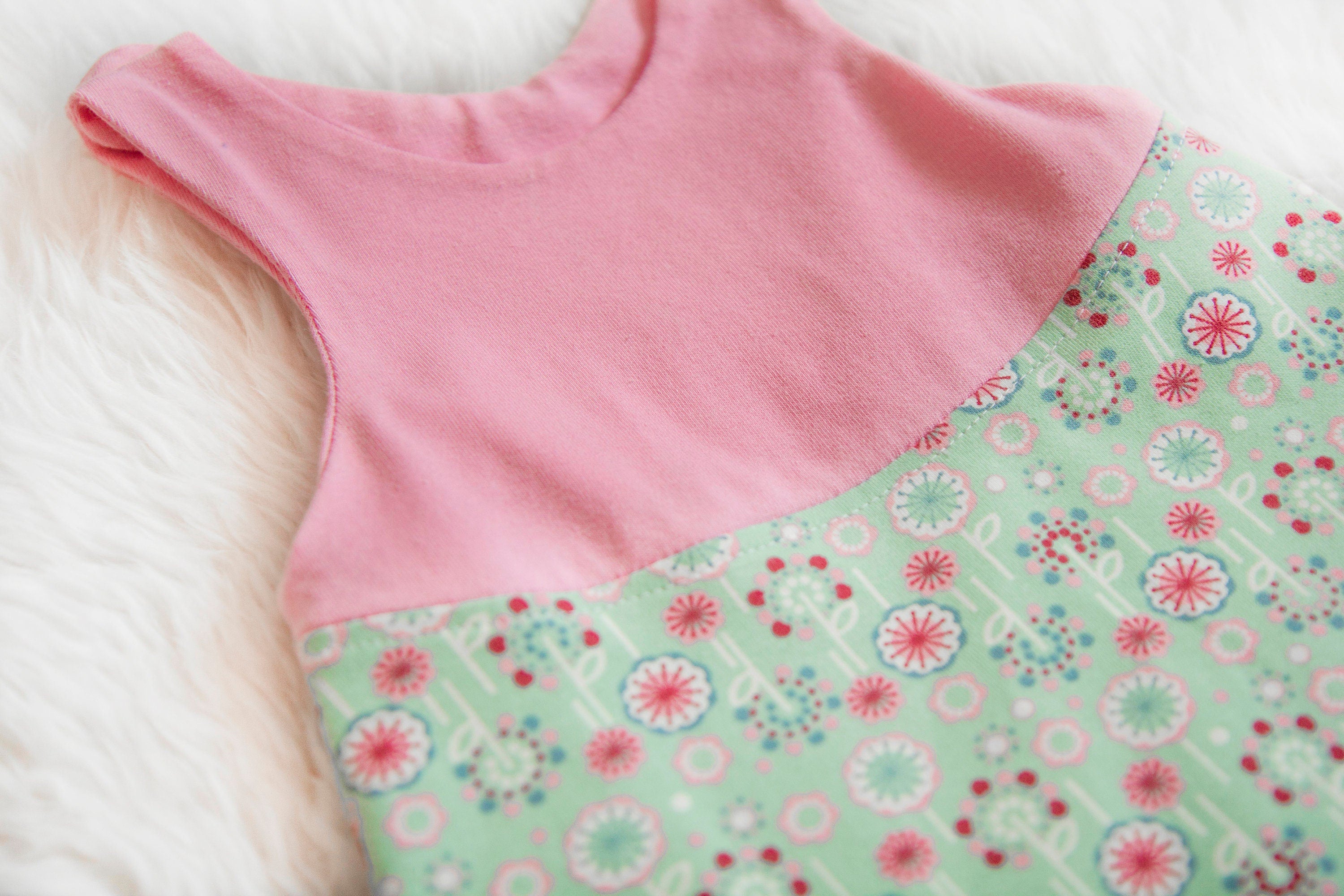 Zweigeteilt, oben rosa unten mint mit Blumen in rosa. Passende Bündchen in rosa.
