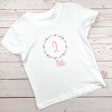 Geburtstagsshirt bestickt mit Blumenkranz und Name. Blumenkranz in den Farben mint, grau und rosa gehalten. Schrift und Zahl in rosa.