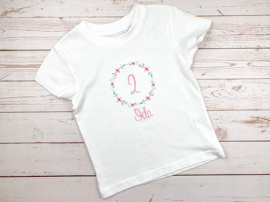 Geburtstagsshirt bestickt mit Blumenkranz und Name. Blumenkranz in den Farben mint, grau und rosa gehalten. Schrift und Zahl in rosa.