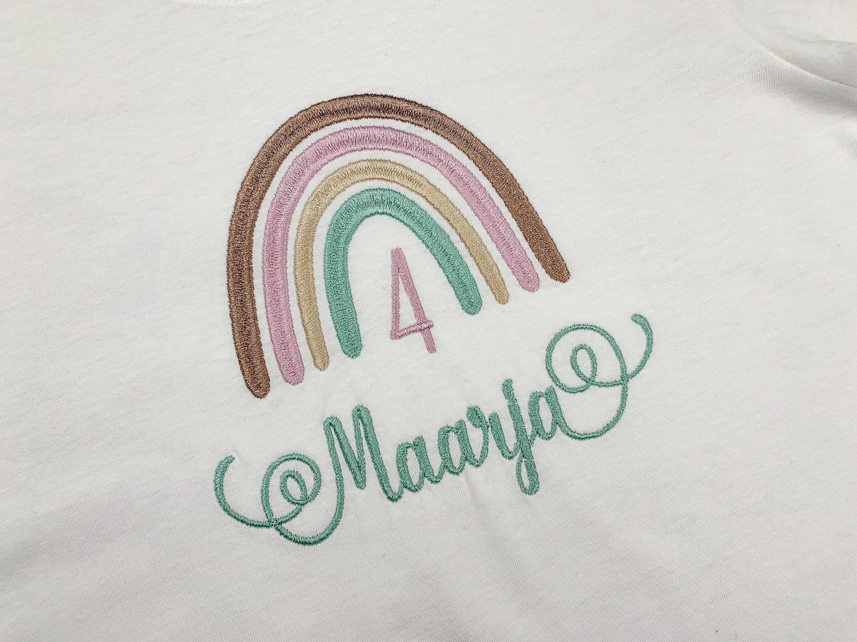 Geburtstagsshirt mit Boho Regenbogen, personalisiert mit Name und Geburtszahl. Farben des Regenbogen - braun, lila, beige, mint. Schrift mit schnörkeln am Anfang und Ende.