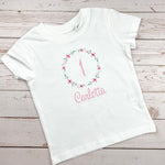 Geburtstagsshirt bestickt mit Blumenkranz und Name. Blumenkranz in den Farben mint, grau und rosa gehalten. Schrift und Zahl in rosa.