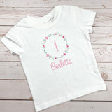 Geburtstagsshirt bestickt mit Blumenkranz und Name. Blumenkranz in den Farben mint, grau und rosa gehalten. Schrift und Zahl in rosa.