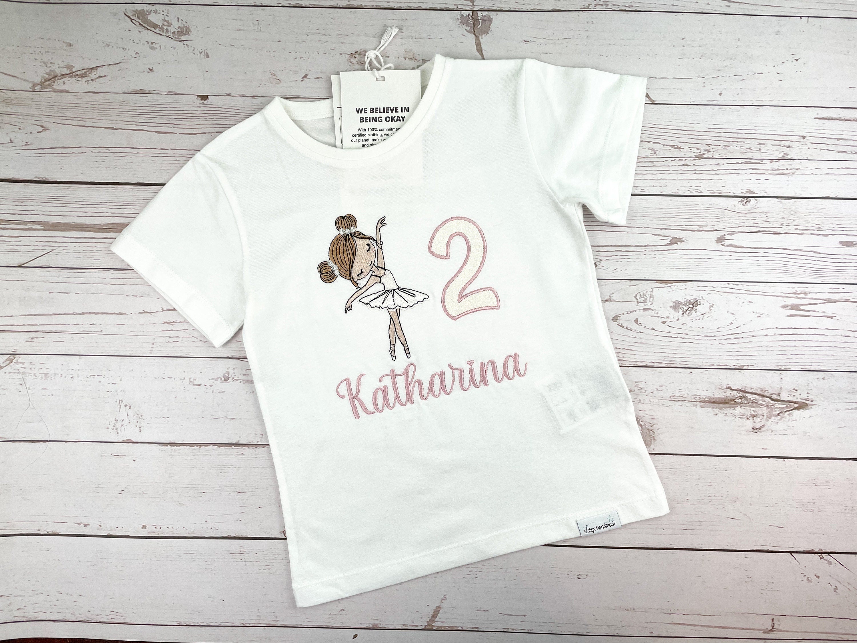 Produkte Geburtstagsshirt bestickt mit Ballerina und Zahl. Zahl mit Glitzerstoff unterlegt. Name in altrosa. 